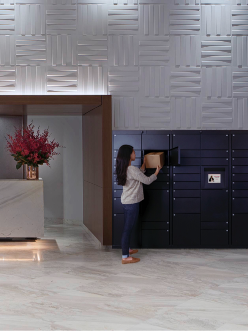 Woman picking up package from Luxer One smart lockers in hotel lobby