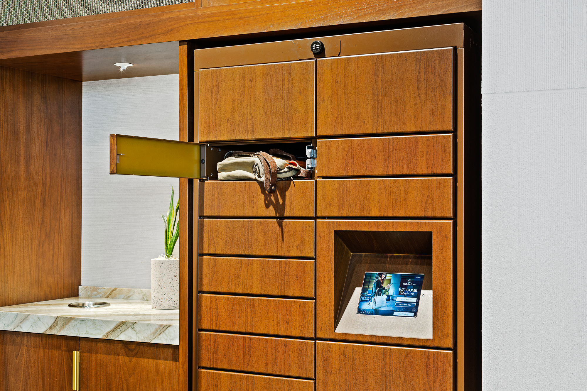 Open smart bag storage locker door showing guests bag in hotel lobby