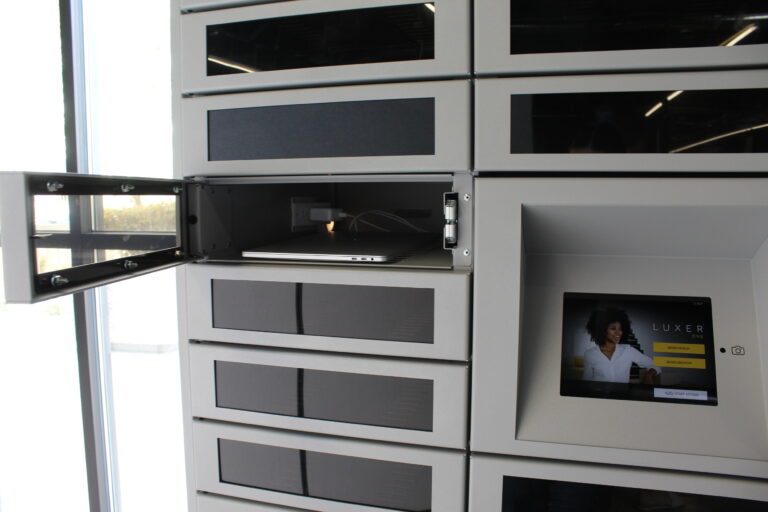 Silver device management smart locker with door open showing a laptop charging inside