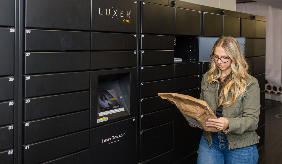 Happy resident removing Amazon package from black Luxer One smart lockers